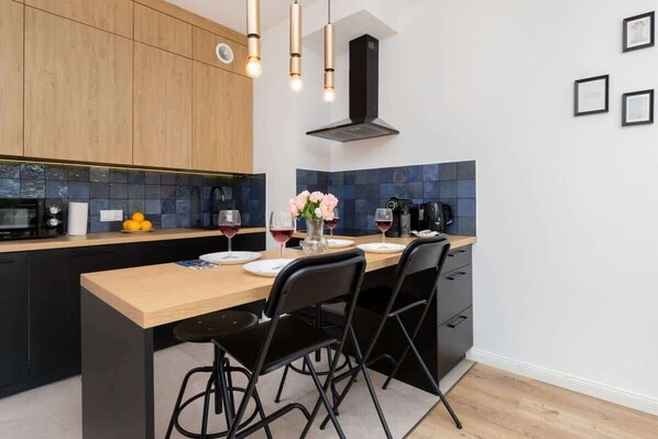 A modern kitchen with wooden cabinets, a black countertop, and a central island with chairs.