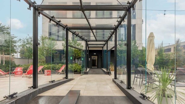 A covered outdoor area with glass walls, a tiled floor, and outdoor seating. - Comfortable Studio in Praga | Parking and Air Conditioning (Warszawa)