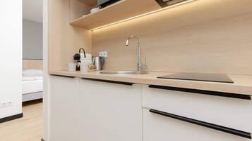 Una cocina moderna con un lavamanos integrado, una cafetera y un hervidor.