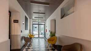 A hotel lobby with a checkered floor, modern chairs, and a door leading to the entrance. - Comfortable Studio in Praga | Parking and Air Conditioning (Warszawa)