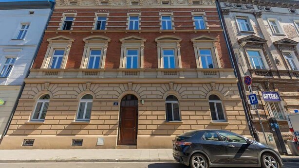A multi-story building with a classic architectural style, featuring a central entrance with a wooden door and arched windows.