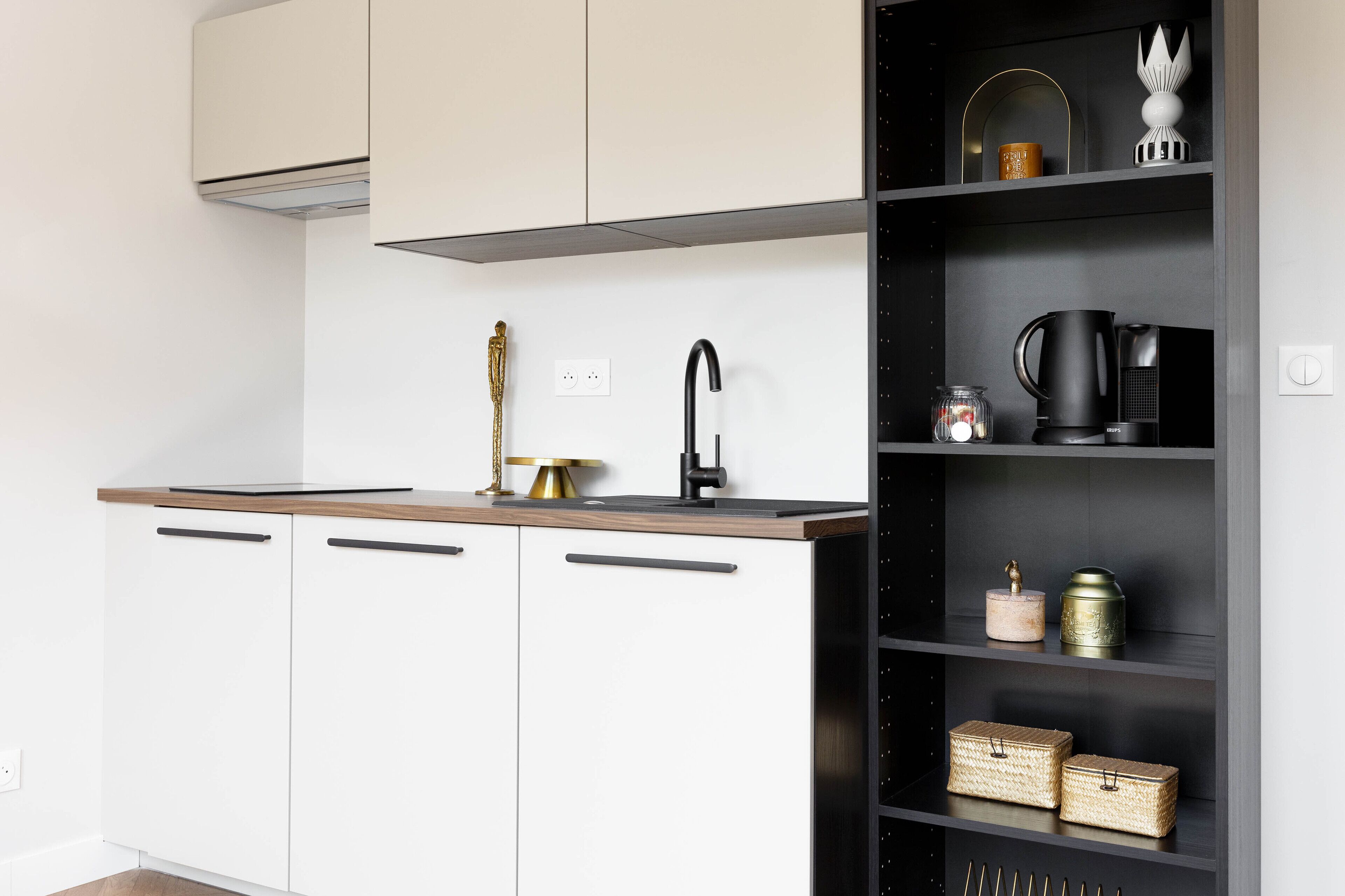 A modern kitchen with white cabinets, a wooden countertop, a black faucet, and a black shelf with kitchen items.
