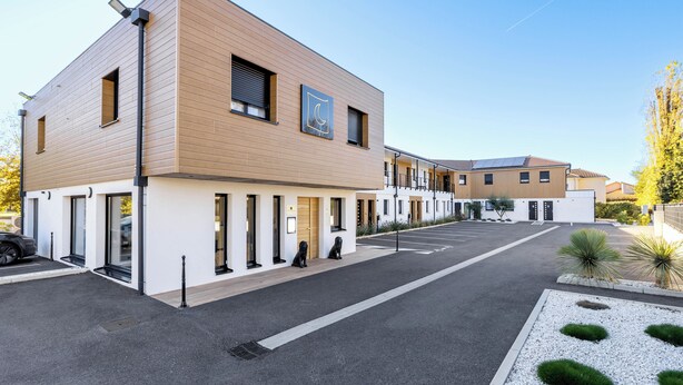 Un bâtiment moderne doté d’un toit plat, de grandes fenêtres et d’un parking.