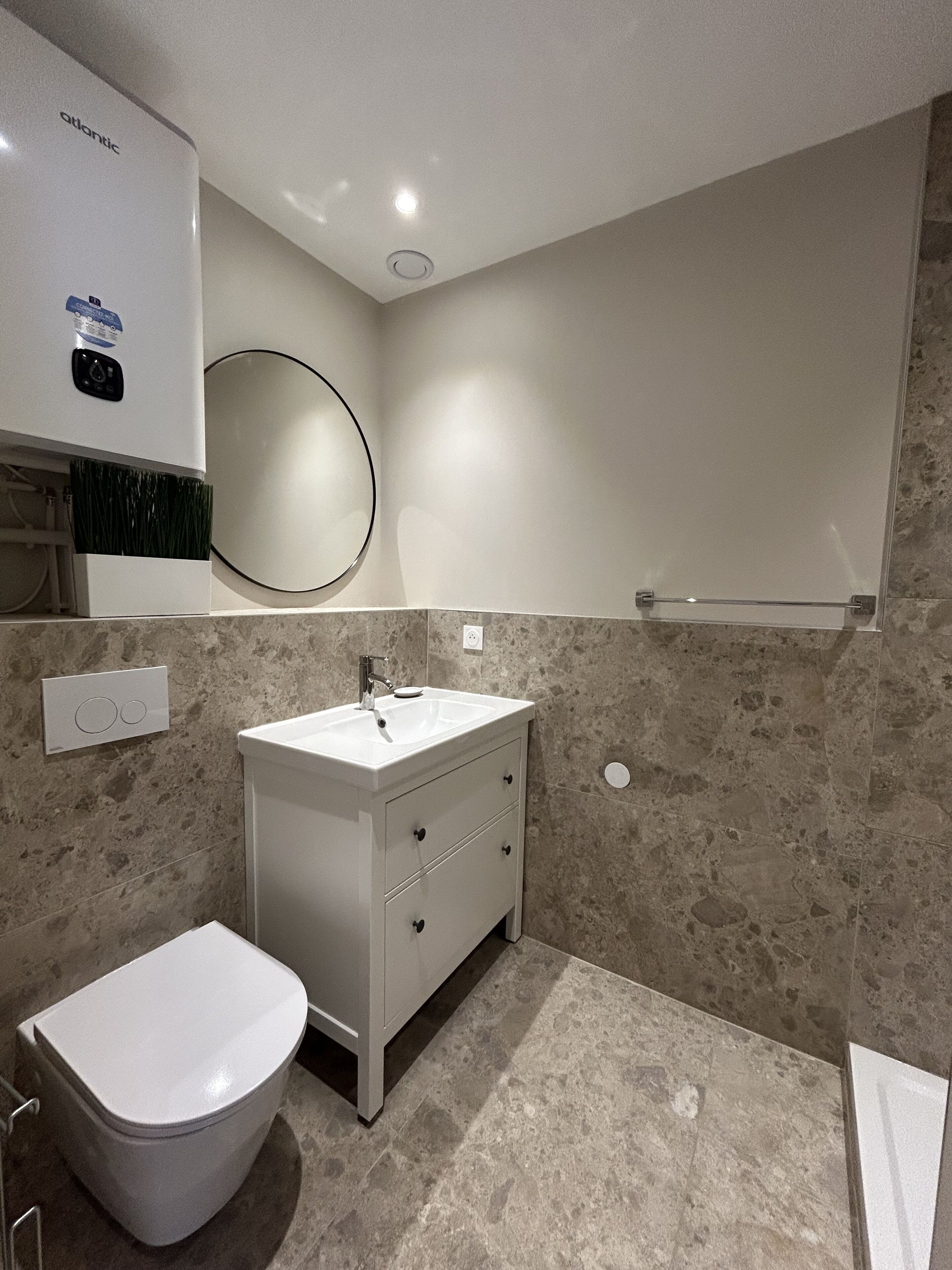 A modern bathroom with a toilet, sink, and mirror.