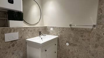 A modern bathroom with a toilet, sink, and mirror.