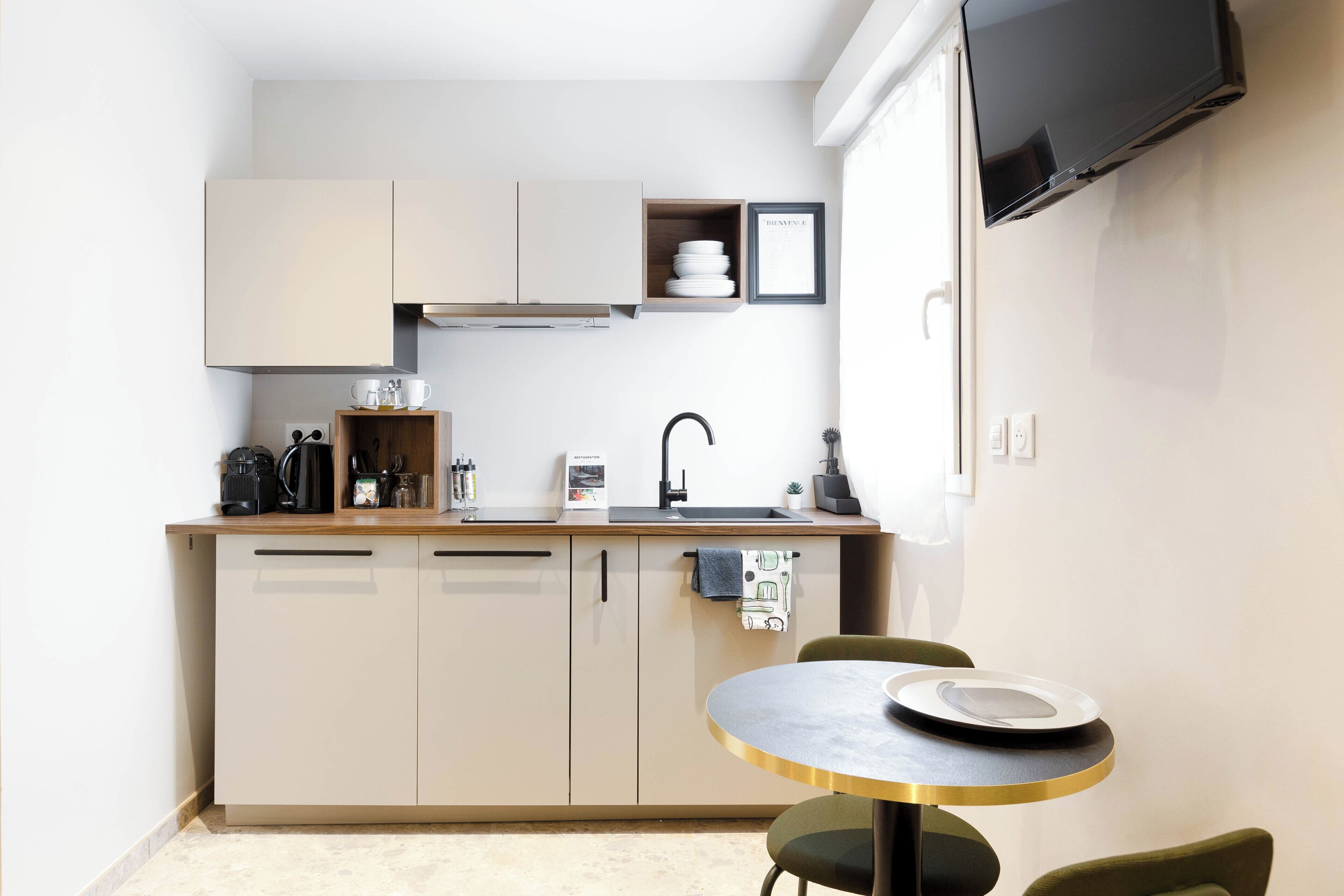 A compact kitchen with a sink, cabinets, and a small dining area with a table and chairs.