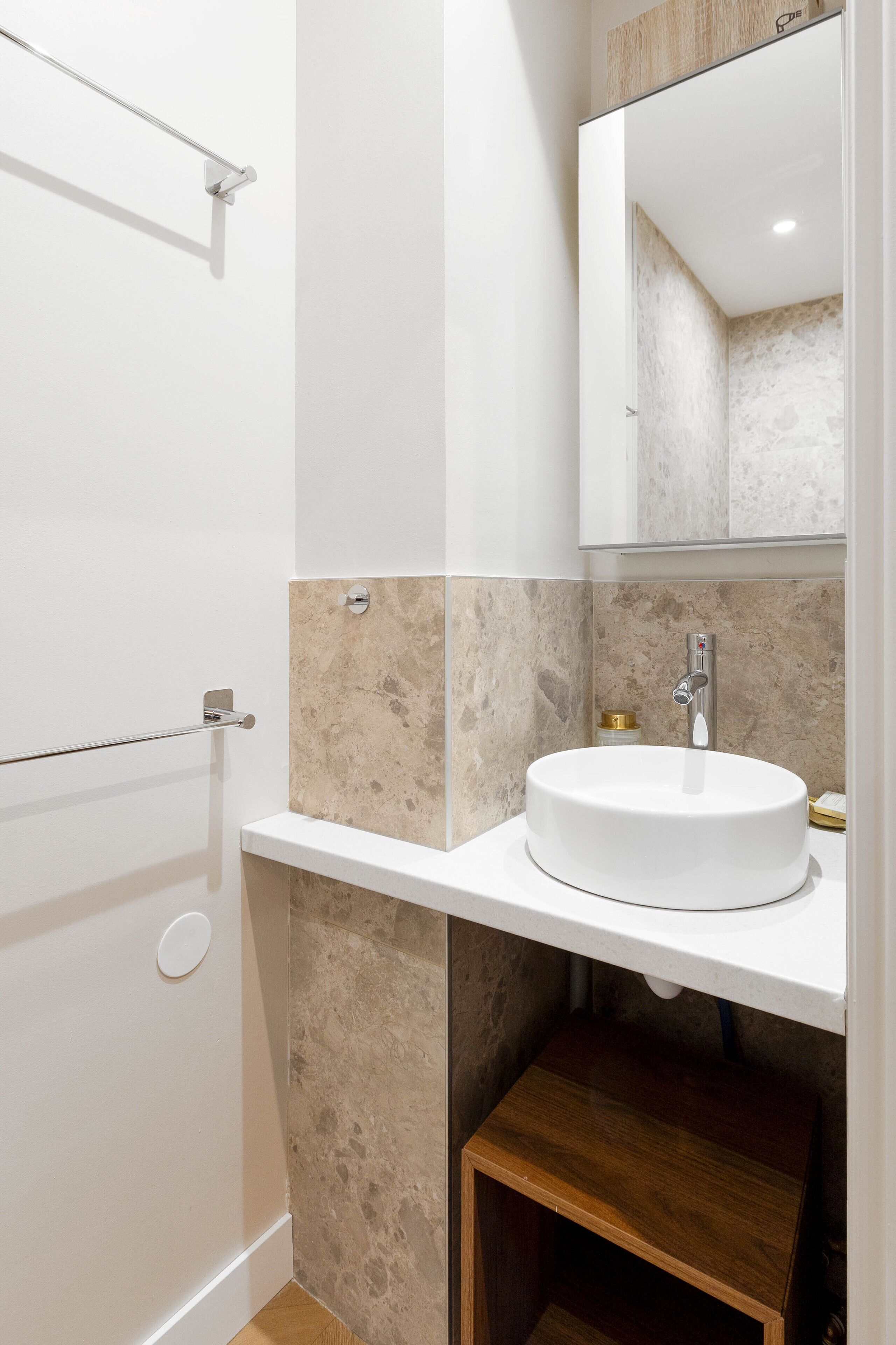 A modern bathroom with a white sink, a mirror, and a shower area.