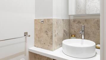A modern bathroom with a white sink, a mirror, and a shower area.