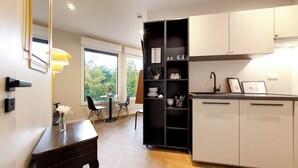 Une cuisine moderne avec des meubles blancs, une étagère noire et un coin repas comprenant une table et des chaises.