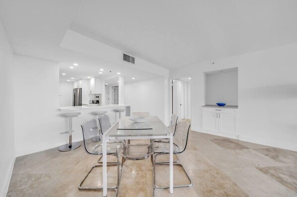 A modern kitchen with white cabinets, a stainless steel refrigerator, and a blue bowl on the counter.