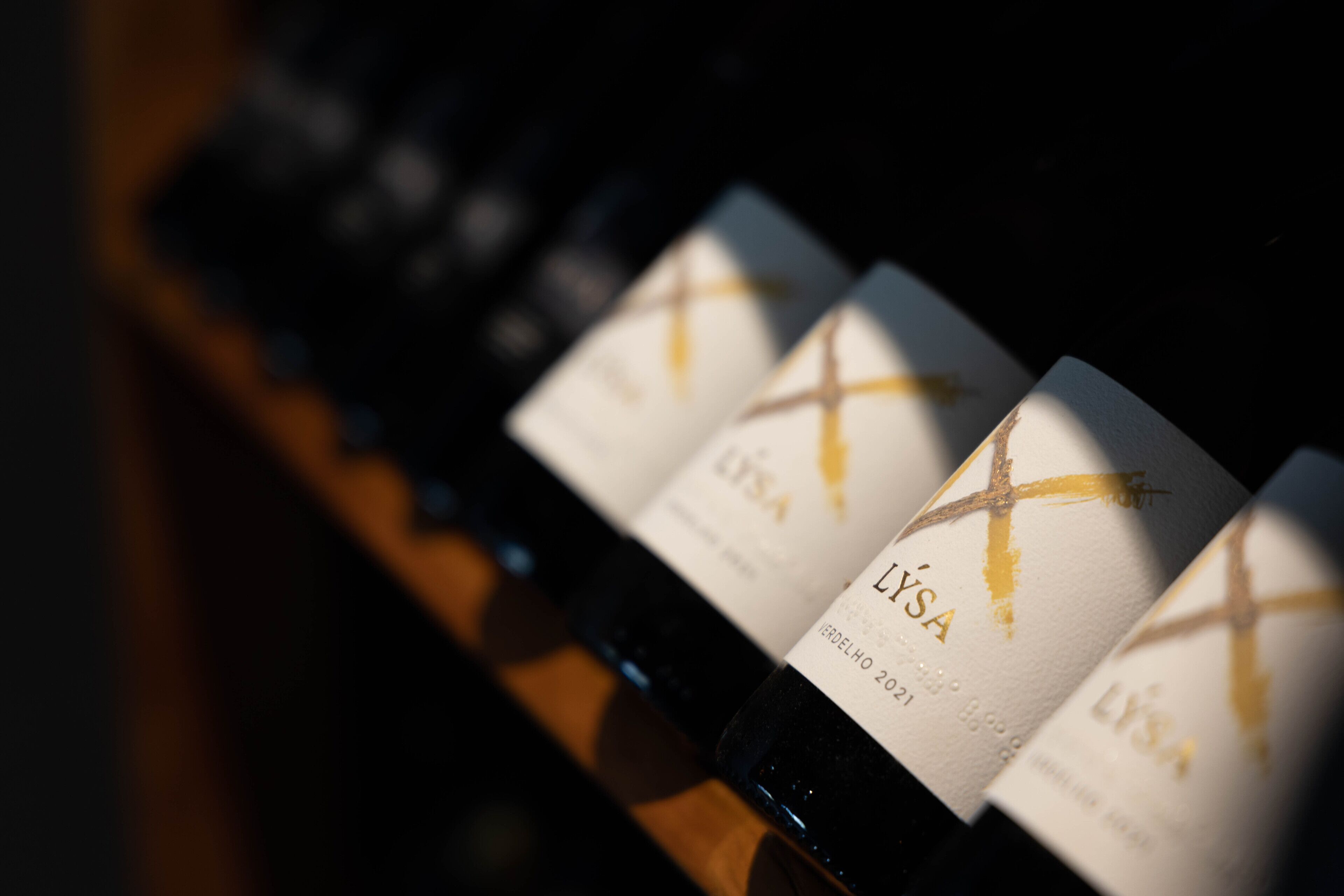 A row of wine bottles with labels, each featuring a gold cross design.