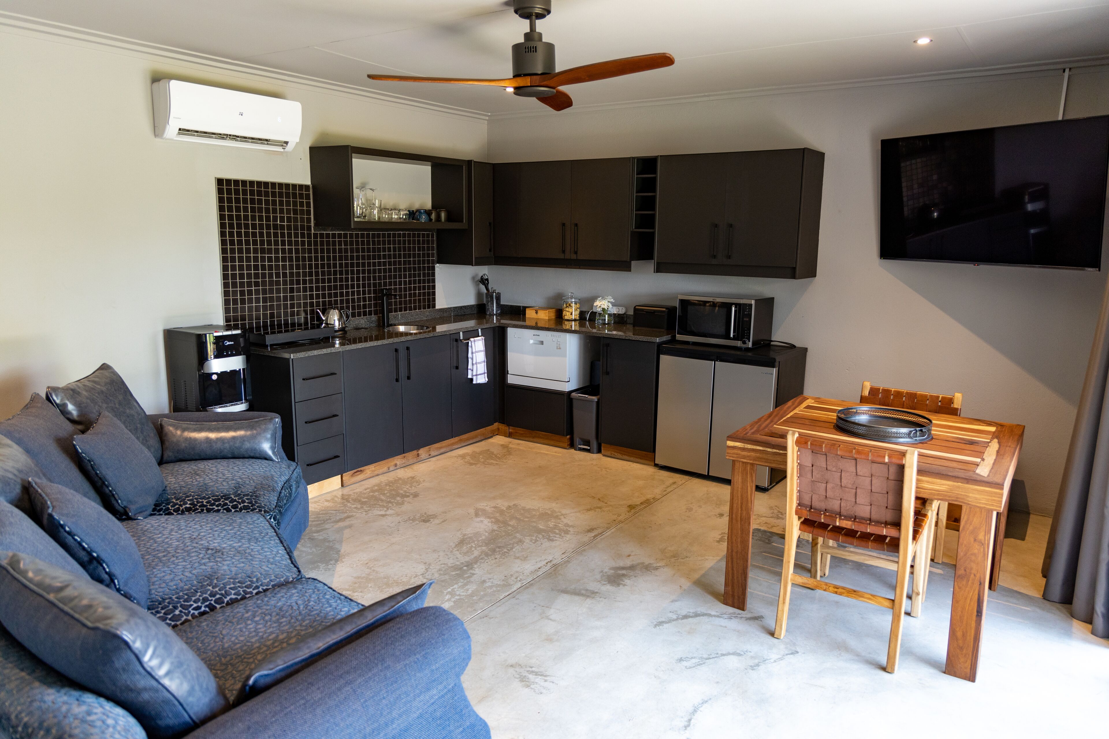 A modern kitchen with dark cabinets, a built-in microwave, and a ceiling fan.