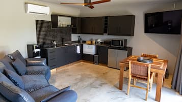 A modern kitchen with dark cabinets, a built-in microwave, and a ceiling fan.