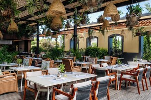 Ein Außenbereich mit Essplatz, Rattanmöbeln, hängenden Pflanzgefäßen und einer Holzterrasse.