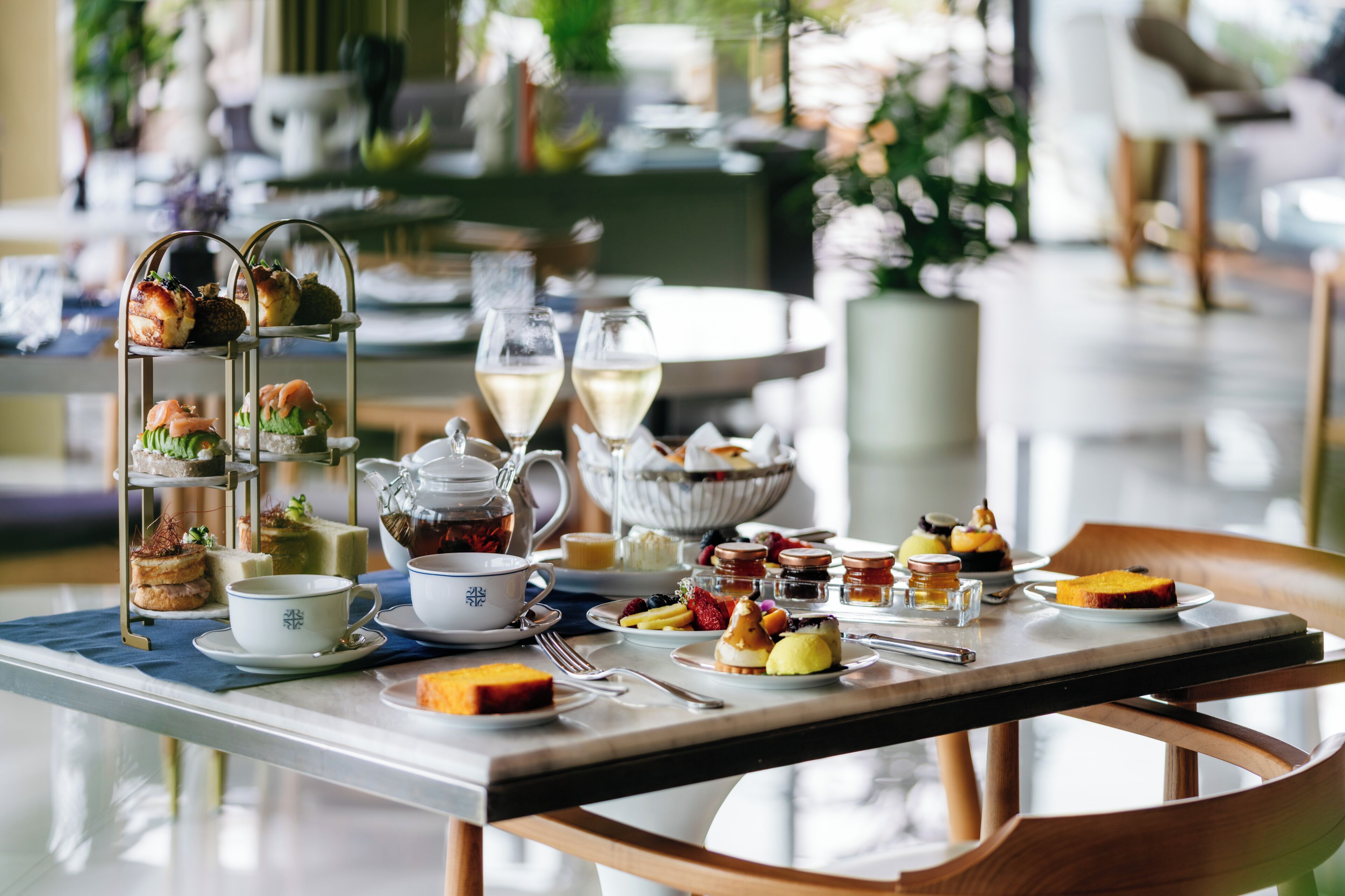 A breakfast table set with various pastries, fruits, and beverages, with a tiered stand holding more pastries.