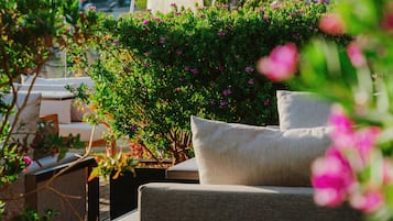 A rooftop terrace with outdoor furniture, a view of a cityscape, and a hill in the background.