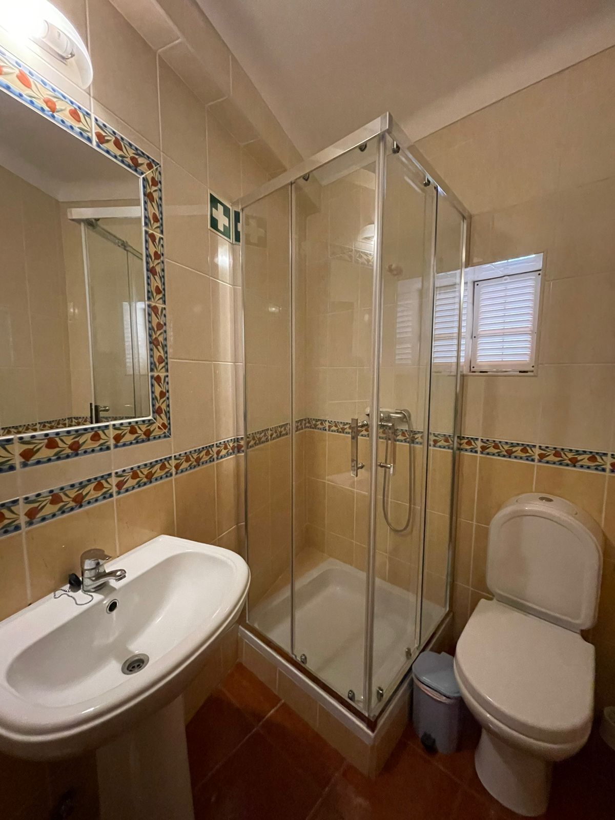 A bathroom with a glass-enclosed shower, a white sink, and a toilet.
