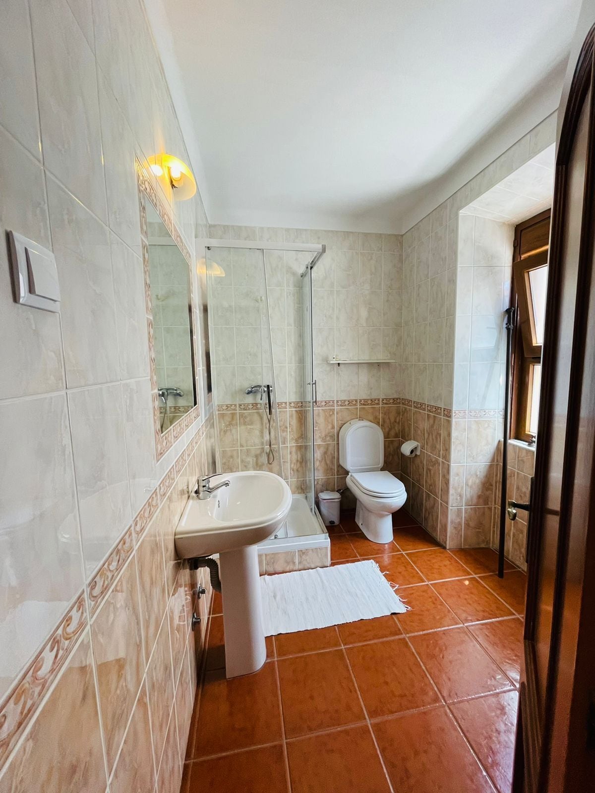 A bathroom with a shower, toilet, sink, and a mirror.