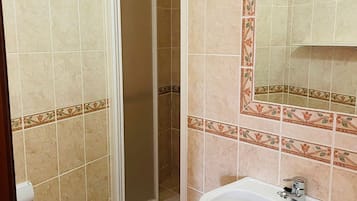 Une salle de bain équipée d’une douche, de toilettes, d’un lavabo et d’un miroir agrémenté de carreaux décoratifs.