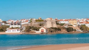 A coastal town with a prominent fortification, a beach, and residential buildings.