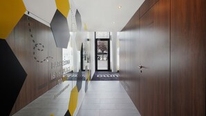 Un couloir moderne avec des motifs géométriques sur les murs et une porte en bois.