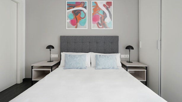 Une chambre d’hôtel moderne avec un grand lit, deux tables de chevet et une œuvre d’art abstraite au mur.