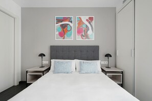 A modern hotel room with a large bed, two bedside tables, and abstract artwork on the wall. - Numa Barcelona Colmena (Barcelona)
