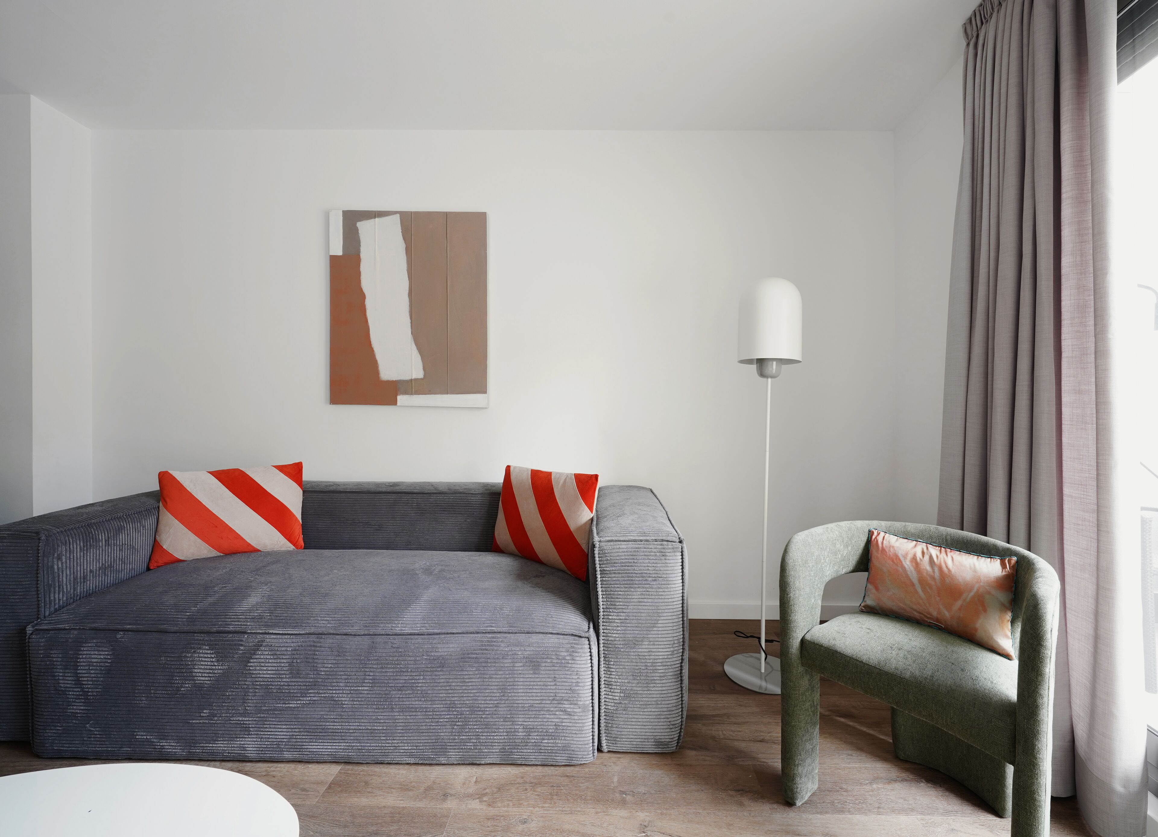 A modern living room with a grey sofa, a green armchair, and a floor lamp.