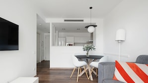 Un salon moderne avec un canapé gris, une table basse blanche et un coin repas comprenant une table et des chaises blanches.