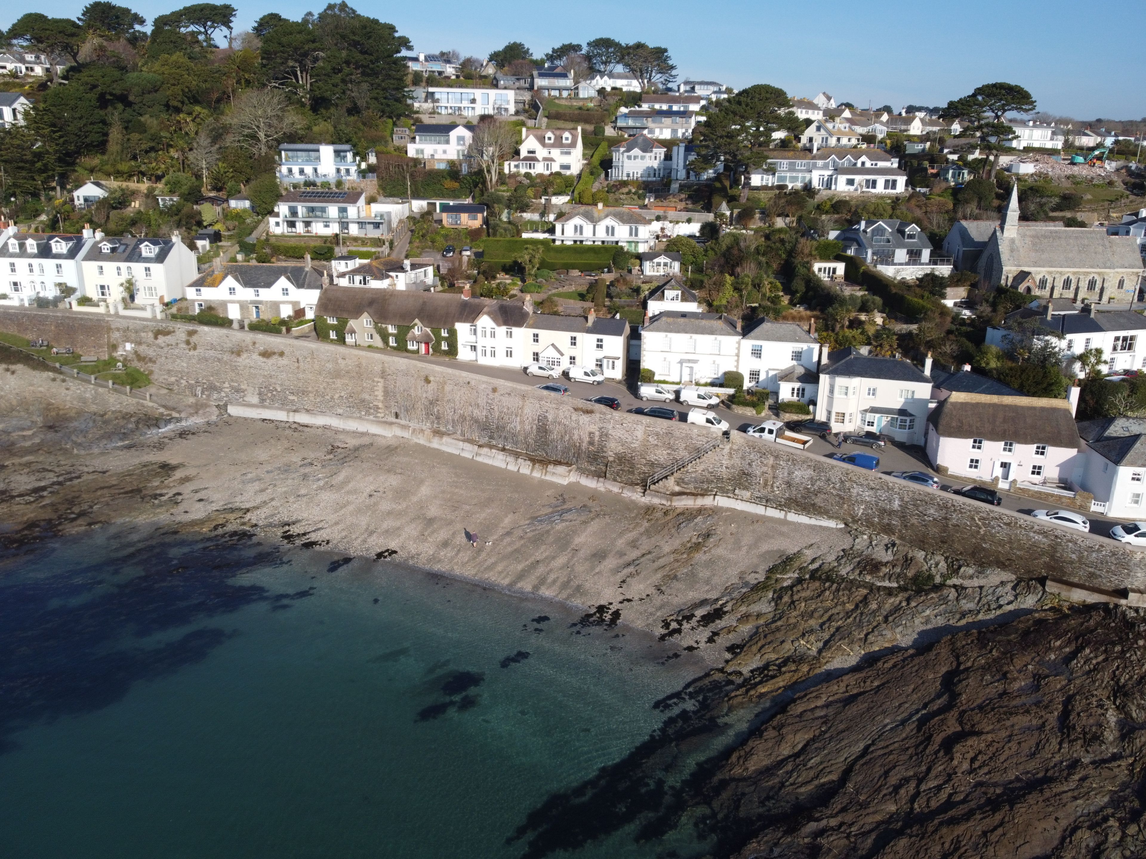 Une ville côtière avec des maisons blanches, un mur de pierre et une plage.