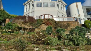 Une grande maison moderne, dotée d’une imposante baie vitrée et d’un mur de soutènement en pierre.