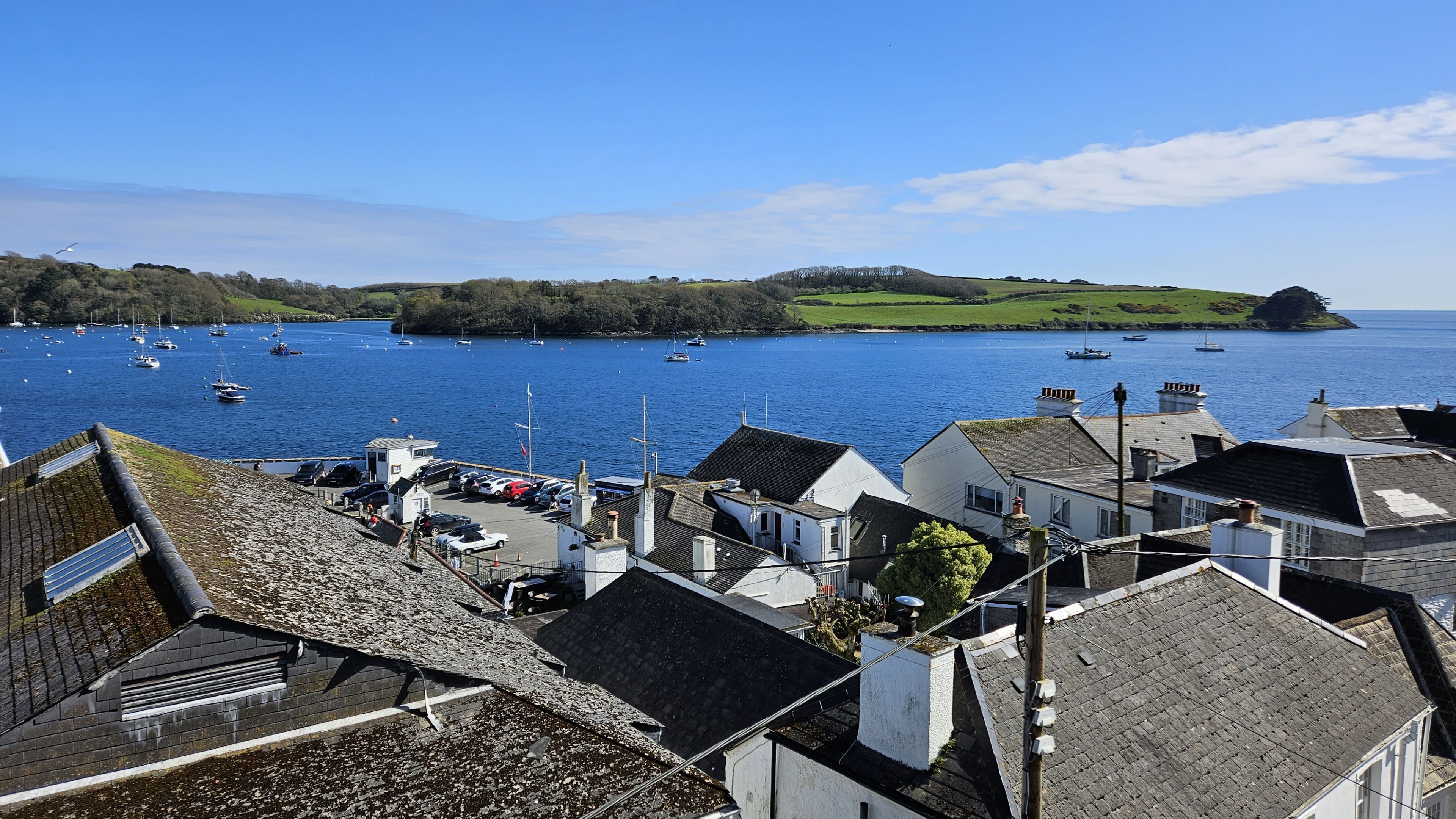 A coastal town with a marina, houses with sloped roofs, and a clear view of the sea.