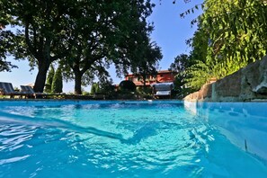 Ein Schwimmbecken mit Liegestühlen und ein rotes Gebäude im Hintergrund.