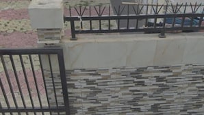 A building with a tiled exterior, a gated entrance, and a pathway leading to a door.