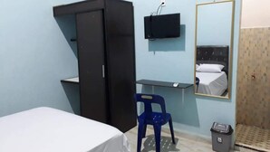 A room with a bed, a desk, a wardrobe, a chair, a television, and a mirror.