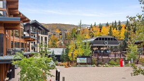 A modern building with a ski lift, surrounded by trees with autumn foliage.