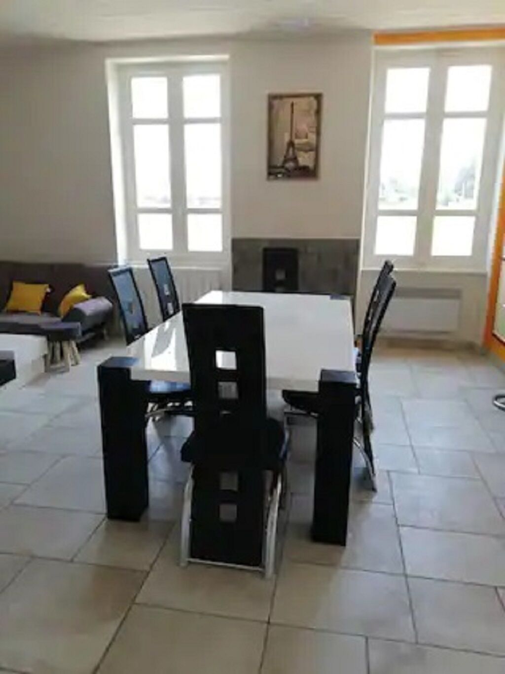 A dining area with a table and chairs, a sofa, and a fireplace.