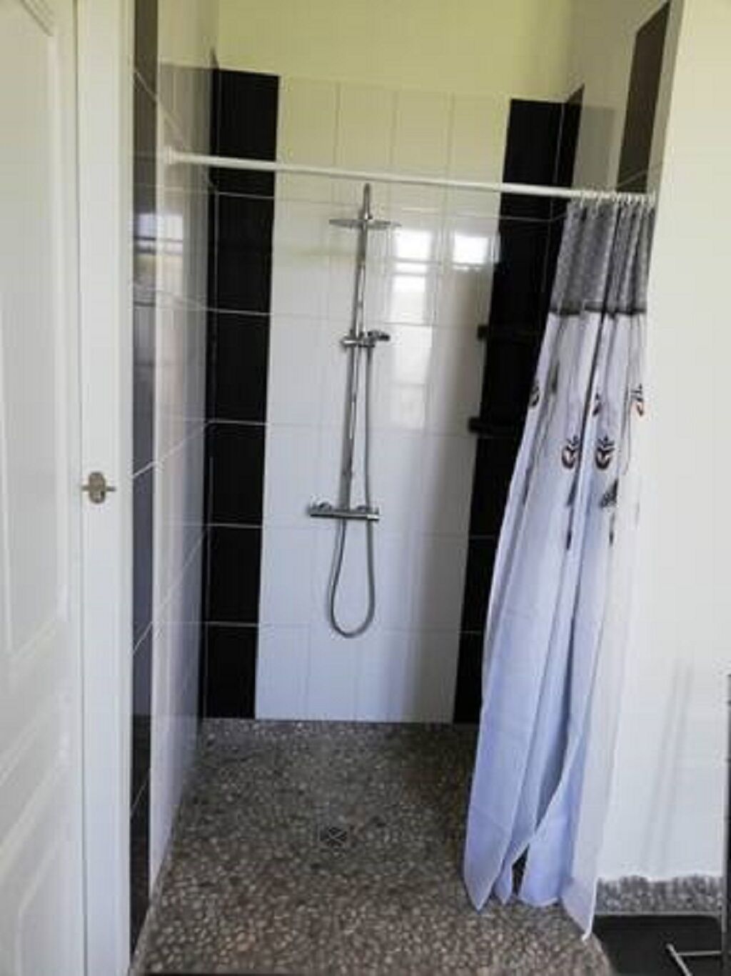 Un bagno piccolo rivestito di piastrelle, con doccetta e tenda.