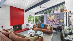 A modern living room with a fireplace, a large colorful painting, and a cozy seating area. - Private Las Palmas Hideaway - Luxury Meets History: Iconic Design with Stunning Mountain Views (Palm Springs)