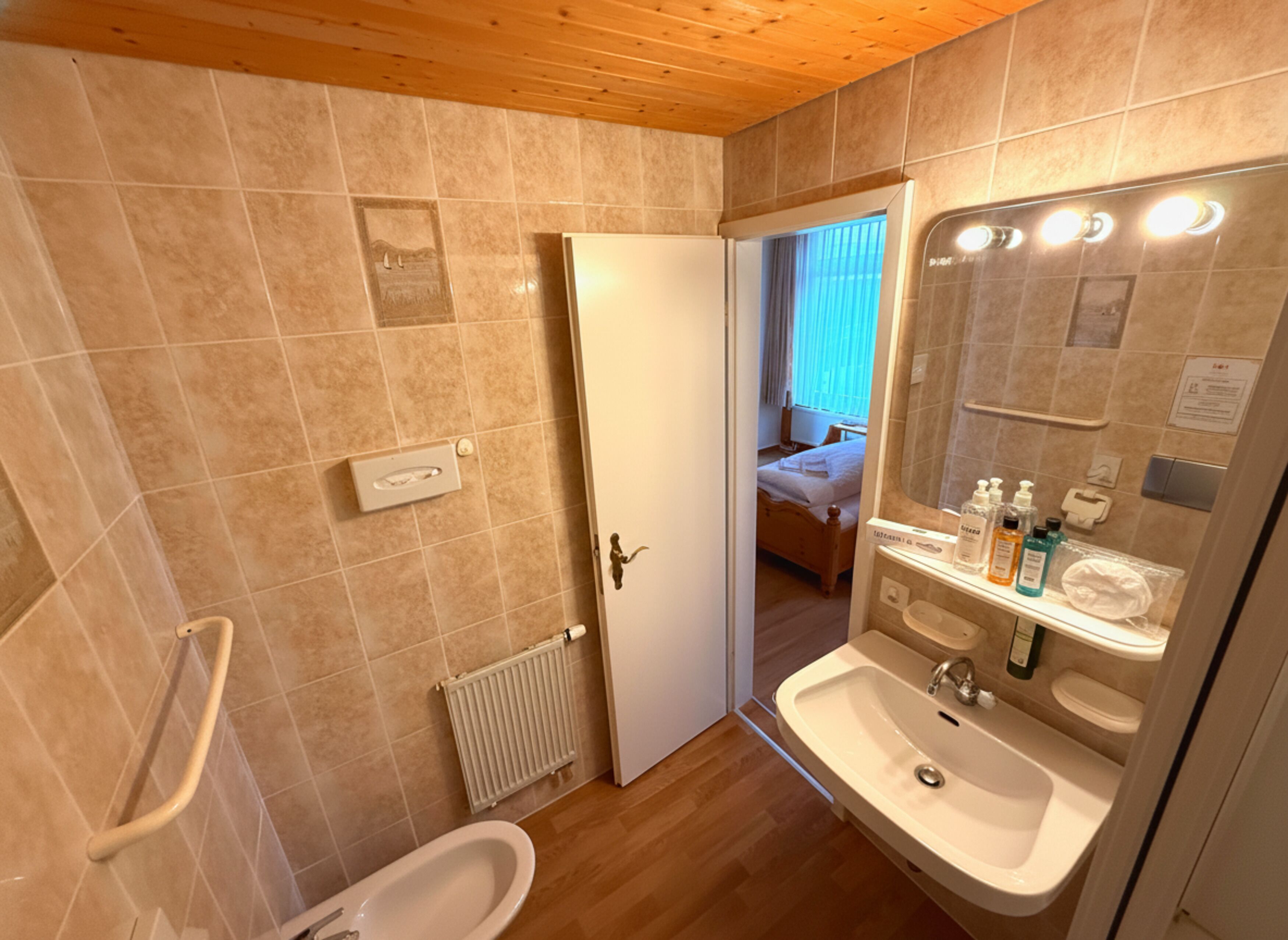 Un baño con ducha, inodoro, lavabo y espejo con iluminación.