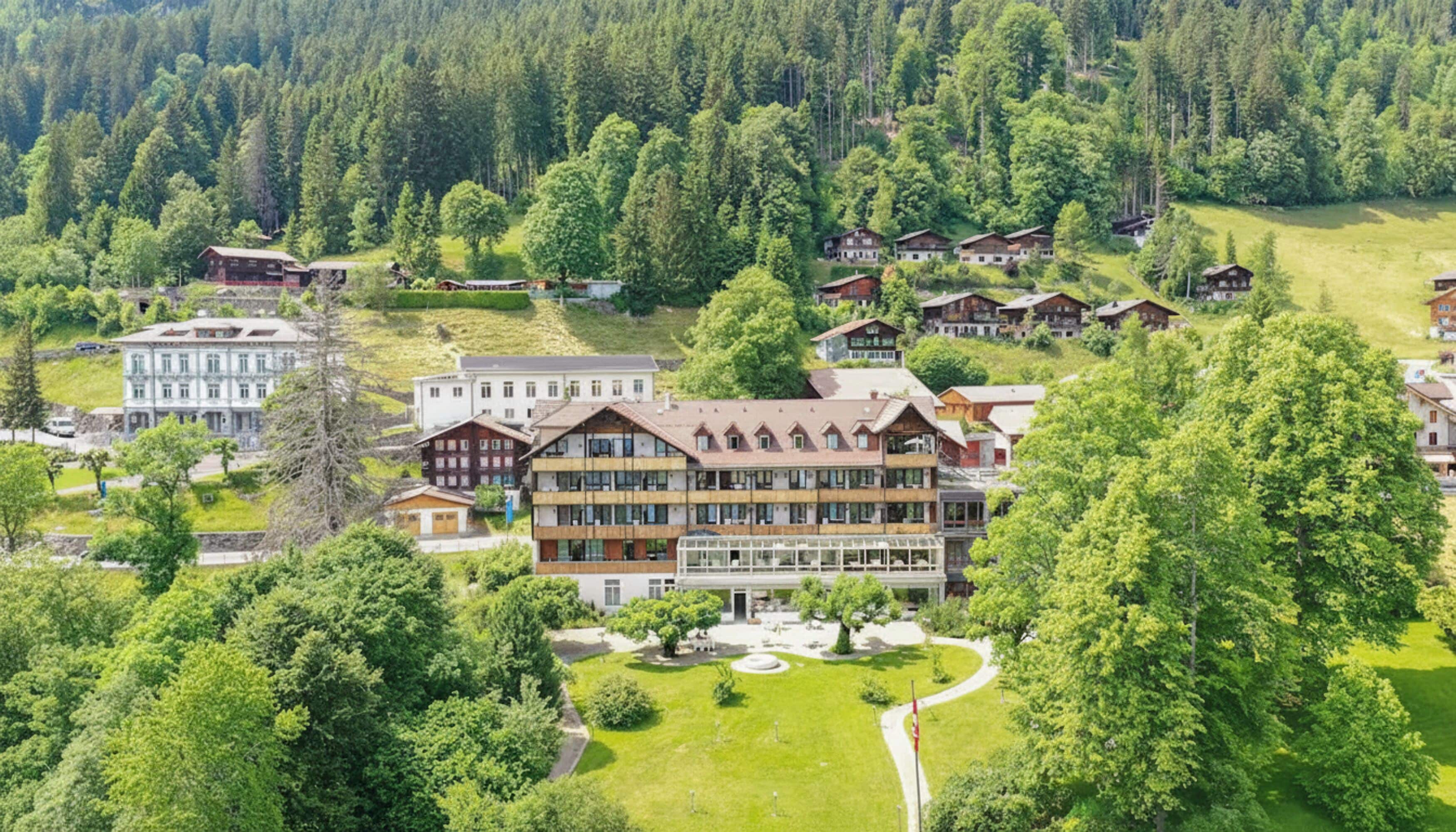 A resort with multiple chalet-style buildings surrounded by lush greenery and forested hills.