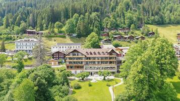 A resort with multiple chalet-style buildings surrounded by lush greenery and forested hills.