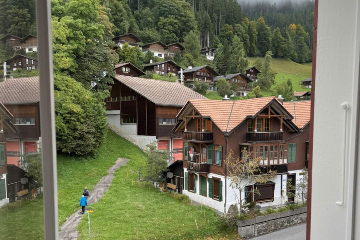 Vista de una zona residencial con casas, una persona caminando y una calle.