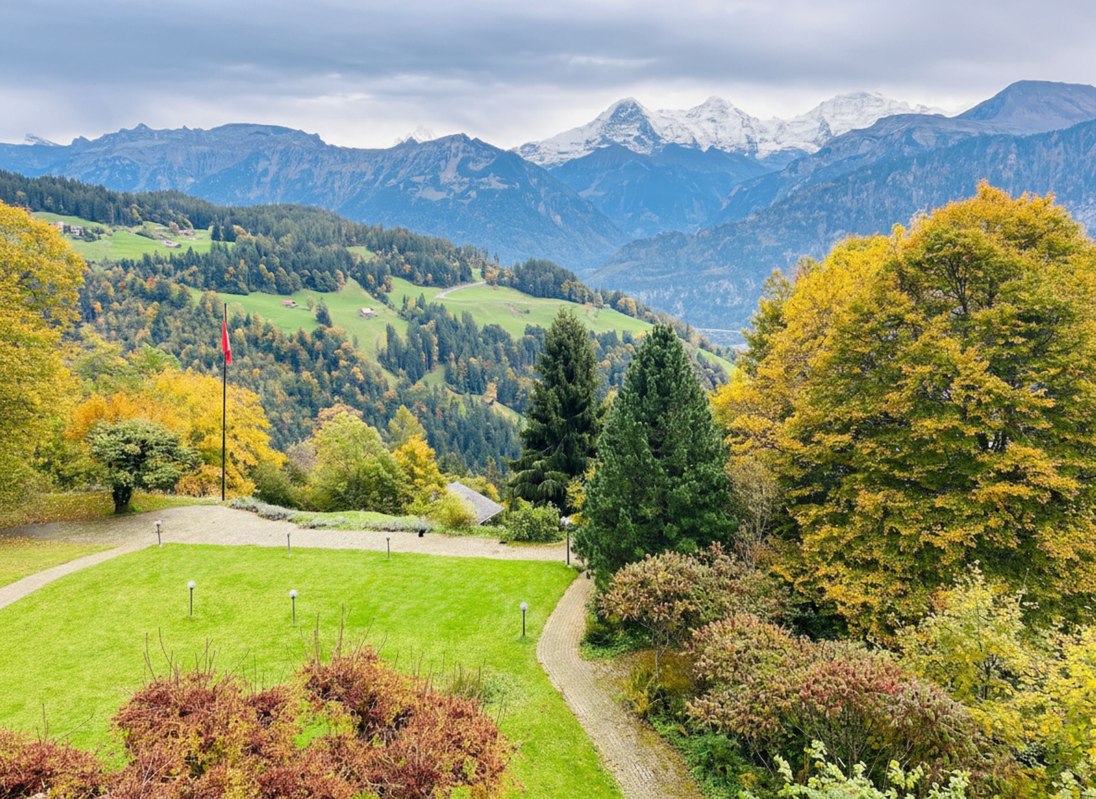 Un paysage pittoresque de montagnes, avec une zone herbeuse et des arbres aux couleurs automnales.