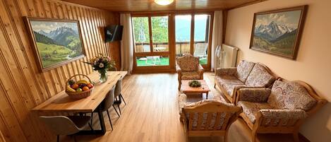 Un interior de madera con una mesa de comedor, sillas, un sofá y dos cuadros.