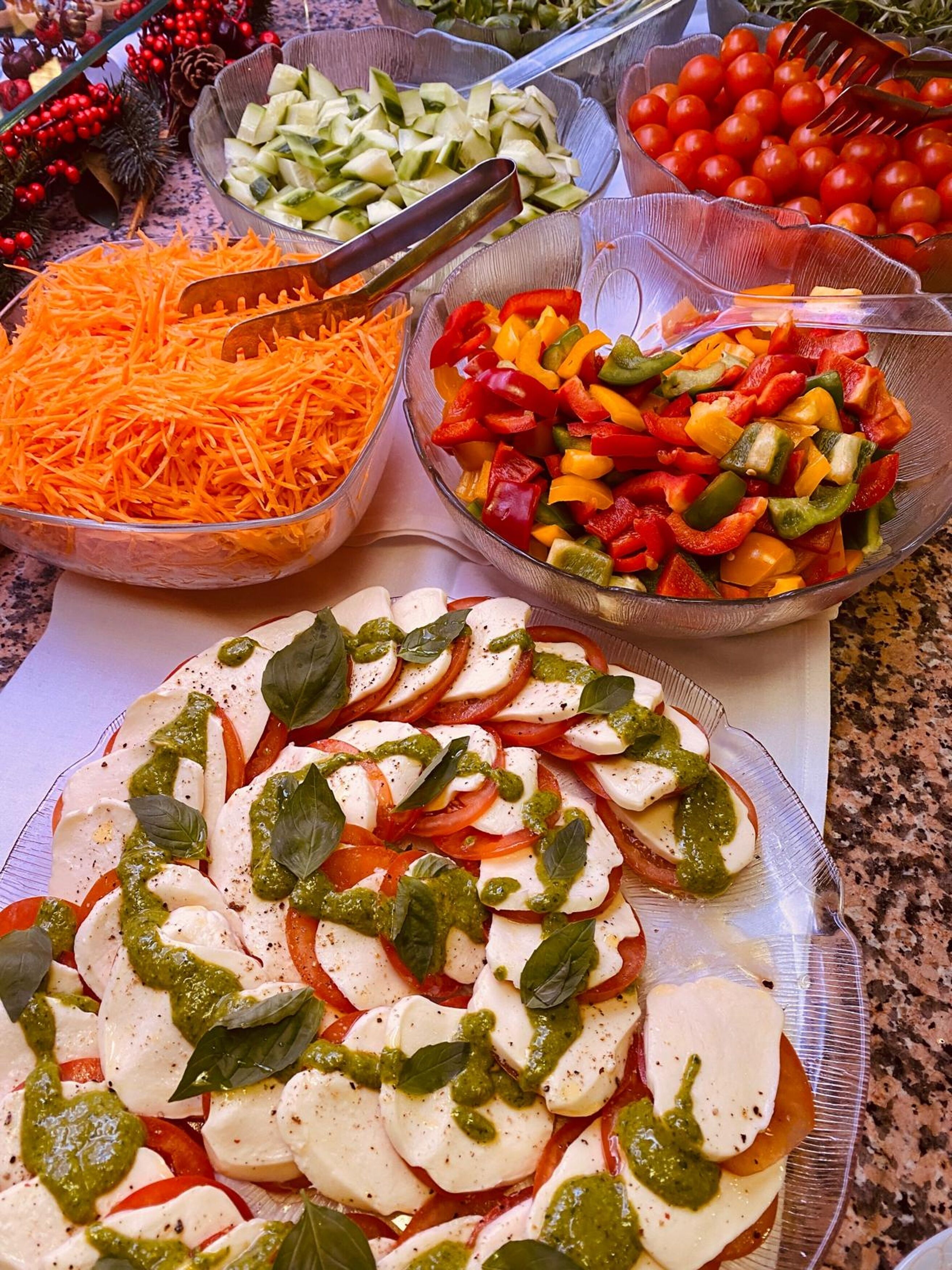 A table with various food items including sliced tomatoes, cucumbers, bell peppers, and shredded carrots.