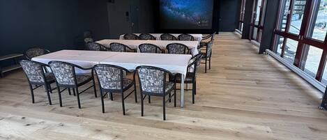 A conference room with a large screen displaying a starry sky, wooden flooring, and modern chairs.