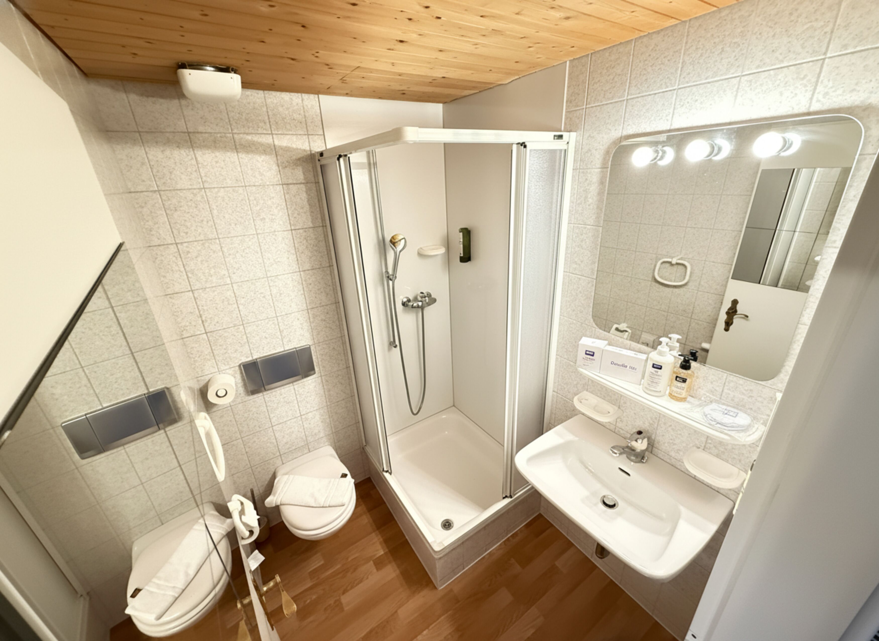 Un baño moderno con ducha, inodoro, lavamanos y un espejo con luces.