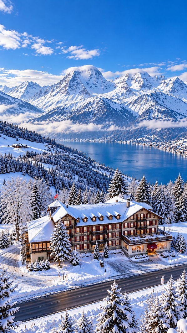A snow-covered lodge with a view of a lake and mountains.
