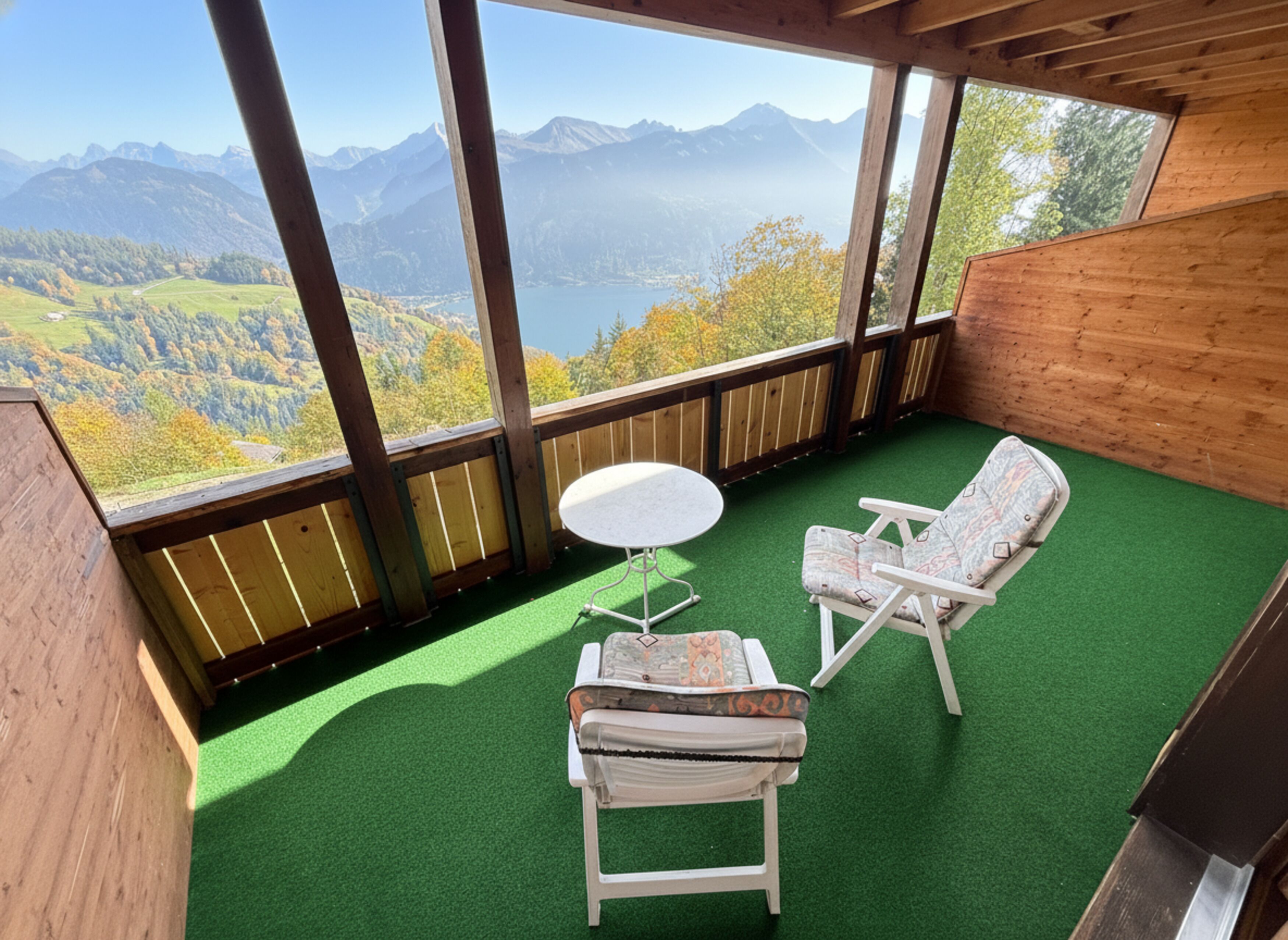 A balcony with a view of mountains, a small round table, and two chairs.